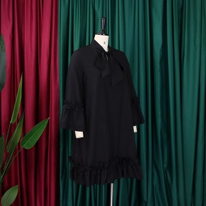 Detail of elegant black dress with bow-tie collar and double-layered ruffle hemline