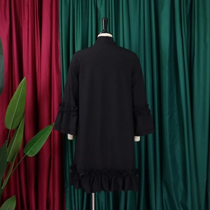Detail of black A-line dress with ruffled cuffs and hem on a mannequin display