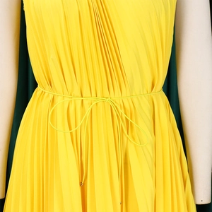 Detail of yellow pleated dress featuring a delicate waist tie and soft chiffon texture