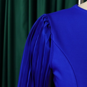 Detail of royal blue pleated shoulder design and silky fabric on long sleeve dress