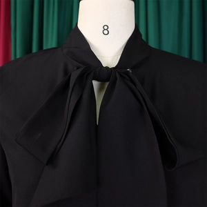 Detail of elegant black dress showing the bow-tie neckline and draped chiffon fabric