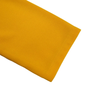 Detail of elegant ginger yellow pleated dress showing neat stitching and chiffon fabric texture