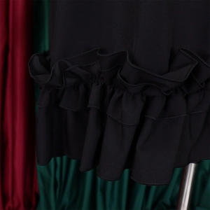 Detail of tiered ruffle hem and pleats on a black loose-fit dress with high-quality stitching