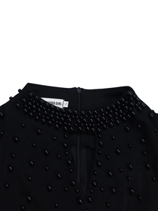Detail of high neck black dress featuring elegant beadwork and keyhole chest cutout
