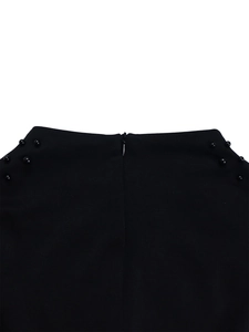 Detail shot of invisible zipper and symmetrical black beadwork on high-waisted dress
