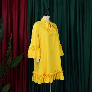 Dettaglio dell'abito giallo in chiffon con fiocco sullo scollo e maniche a balze