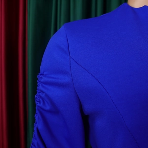 Détail de robe bleue à col en V présentant des manches plissées élégantes et un tissu sergé