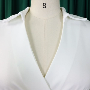 Nahaufnahme des eleganten V-Ausschnitts und Reverskragens an einem weißen Maxikleid