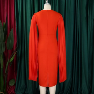Detail view of orange pleated shawl sleeves and slit hem on slim fit midi dress