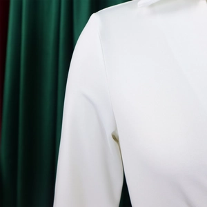 Detailaufnahme der weißen Langarmkleid-Stoffstruktur mit feinem Webmuster und Nähten
