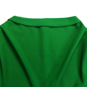 Close-up of the elegant green pleated dress featuring a classic notched lapel and textured fabric