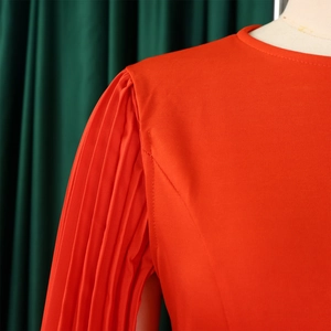 Detail of red elegant pleated long sleeves and shoulder texture on a round neck dress