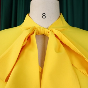 Dettaglio dell'elegante abito giallo con scollo a V e un grande fiocco alla moda
