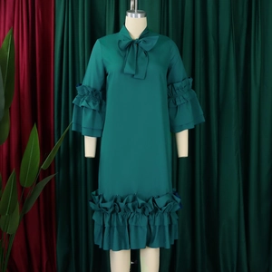Detail of dark green dress showing bow neckline and tiered ruffle flare sleeves