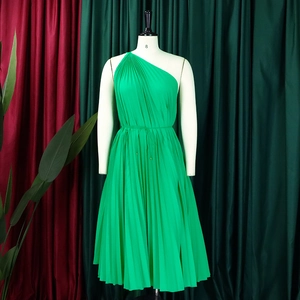 Detail of bright green pleated one-shoulder dress with matching gold bead waist tie