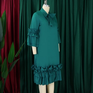 Detailed view of the dark green dress featuring tiered ruffle sleeves and a bow neckline
