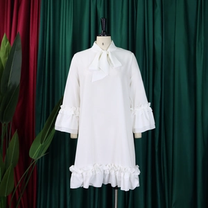Dettaglio di abito bianco con eleganti maniche a balze e grande fiocco sullo scollo
