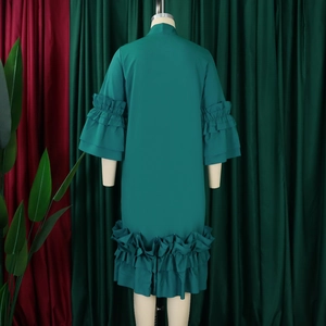 Detail view of dark green dress featuring elegant ruffled flared sleeves and smooth fabric