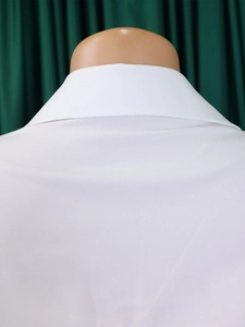 Close-up of the back collar on a white cotton pleated dress with high-quality stitching