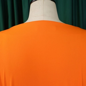 Detailed close-up of vibrant orange V-neck shirt neckline and woven fabric texture