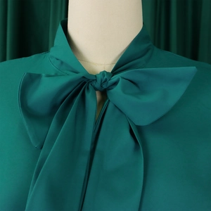 Close-up detail of dark green dress with elegant bow collar and soft chiffon texture