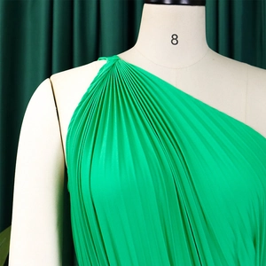 Close-up of bright green pleated fabric and asymmetric one-shoulder design detail