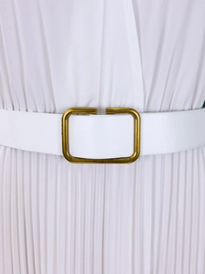 Detail of white pleated dress with a minimalist gold buckle on a matching belt