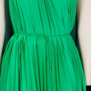 Macro shot of green pleated dress waist with a slim belt and golden bead detailing