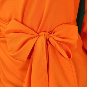 Detail of a bright orange blouse featuring a large decorative waist bow and fine stitching