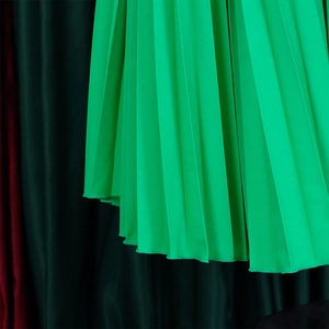 Detailed close-up of vibrant green pleated fabric with elegant silk-like sheen texture