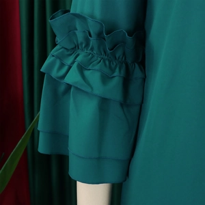 Detail of dark green dress showing layered ruffle flare sleeves and chiffon fabric texture