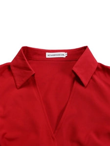 Detail of red lapel V-neckline with brand label on textured fabric African dress