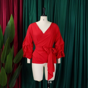 Detail of red V-neck wrap blouse featuring tiered ruffle sleeves and waist tie bow