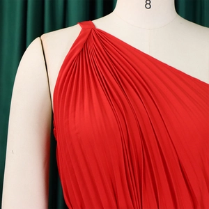 Close-up of red one-shoulder pleated fabric with sharp vertical texture and flow