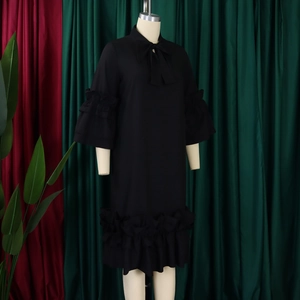 Detail view of black dress featuring ruffled bell sleeves and stylish bowtie neckline