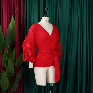Detail of red V-neck wrap blouse with puff sleeves and self-tie waist on mannequin