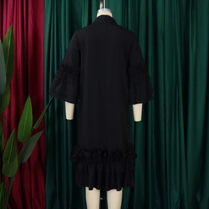 Detail view of the double-layered ruffle sleeves and loose hem on this black shift dress