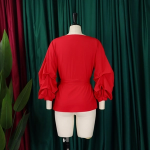 Detail of red lantern sleeve blouse showing ruffled texture and matching waist belt
