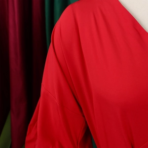 Detail of red off-shoulder puff sleeves with silky sheen and precise cross stitching