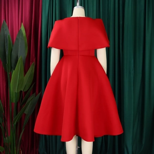Détail d'une robe de cocktail rouge à cape avec taille ajustée et jupe évasée élégante