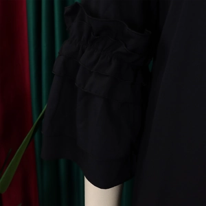Detail of elegant black dress featuring triple-layered ruffle sleeves and airy chiffon fabric
