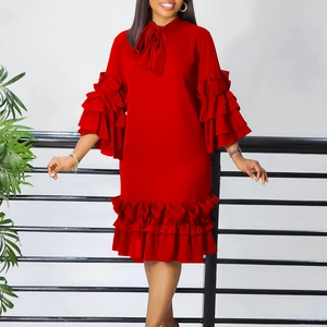 Detail of red tiered dress featuring oversized bow tie neck and layered ruffle sleeves