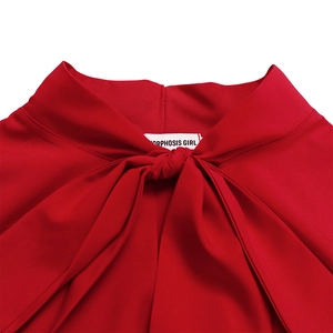 Detail showing the elegant tie-neck bow design and neckline texture of the red dress