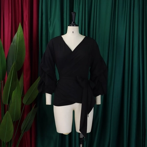 Detail of black wrap top with deep V-neck, puff sleeves and adjustable waist tie
