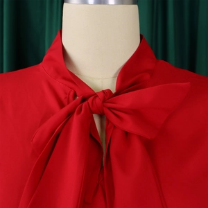 Detail of red stand collar blouse with elegant bow tie neck and soft ruffle sleeves
