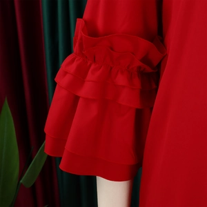 Detail showing the layered ruffle flare sleeves of a stylish red dress on a model