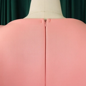 Détail du dos d'une robe rose avec fermeture éclair invisible sur un tissu tissé fin