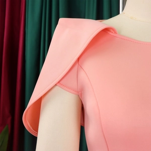 Détail de l'épaule de la robe rose pêche avec un design plissé structuré et élégant