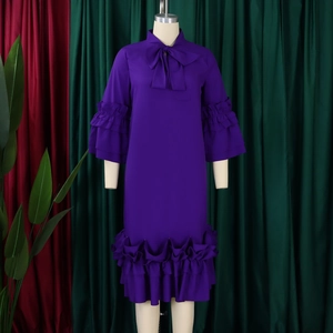 Detail of deep purple dress featuring bow neck tie and ruffled bell sleeves on mannequin