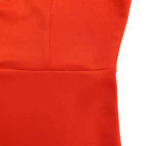 Macro shot of precise stitching and elastic knit texture on an orange-red dress